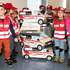 Eine Gruppe Kindergartenkinder posiert mit Rotkreuzwesten und einigen Rettungsautos aus Karton