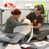 Ein Mann und eine Frau sitzen auf dem Boden und verarzten einen Rotkreuz-Teddybären im Zuge der Erste-Hilfe-Lehrbeauftragten-Ausbildung des Österreichische Jugendrotkreuzes.