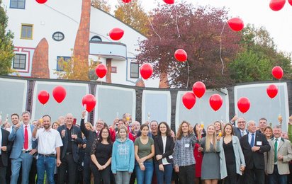 Gruppenfoto der Teilnehmer:innen der ÖJRK-Bundeskonferenz 2011. Einige Personen halten ein Glas Sekt in der Hand und prosten damit zu. Über der Gruppe sind rote Luftballons, die gerade aufsteigen, zu sehen.