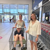 Zwei Mädchen und ein Junge im Supermarkt, der Junge sitzt in einem Einkaufswagen