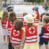 Kinder in roten Warnwesten schauen sich ein Rettungsauto an.