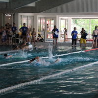 Blick über die Startbahnen mit Schwimmer:innen und Betreuer:innen im Hintergrund