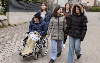 Jugendliche schieben ihren Vater im Rollstuhl 
