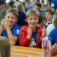 3 Kinder sitzen am Tisch, klatschen und lächeln