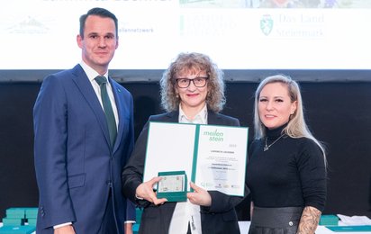 Meilensteinverleihung 2025. Luminita Lechner erhält den Meilenstein und die Urkunde, neben ihr stehen Landesrat Stefan Hermann (links) und Leiterin des Referats Jugend Kerstin Dremel (rechts)