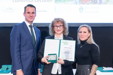 Meilensteinverleihung 2025. Luminita Lechner erhält den Meilenstein und die Urkunde, neben ihr stehen Landesrat Stefan Hermann (links) und Leiterin des Referats Jugend Kerstin Dremel (rechts)