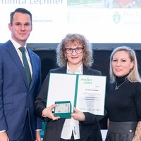 Meilensteinverleihung 2025. Luminita Lechner erhält den Meilenstein und die Urkunde, neben ihr stehen Landesrat Stefan Hermann (links) und Leiterin des Referats Jugend Kerstin Dremel (rechts)