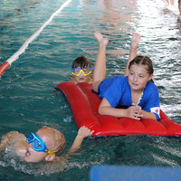 Zwei Kinder ziehen bzw. schieben ein Kind auf einer Luftmatratze im Rahmen der Rettungsstaffel beim Pinguin Cup 2023