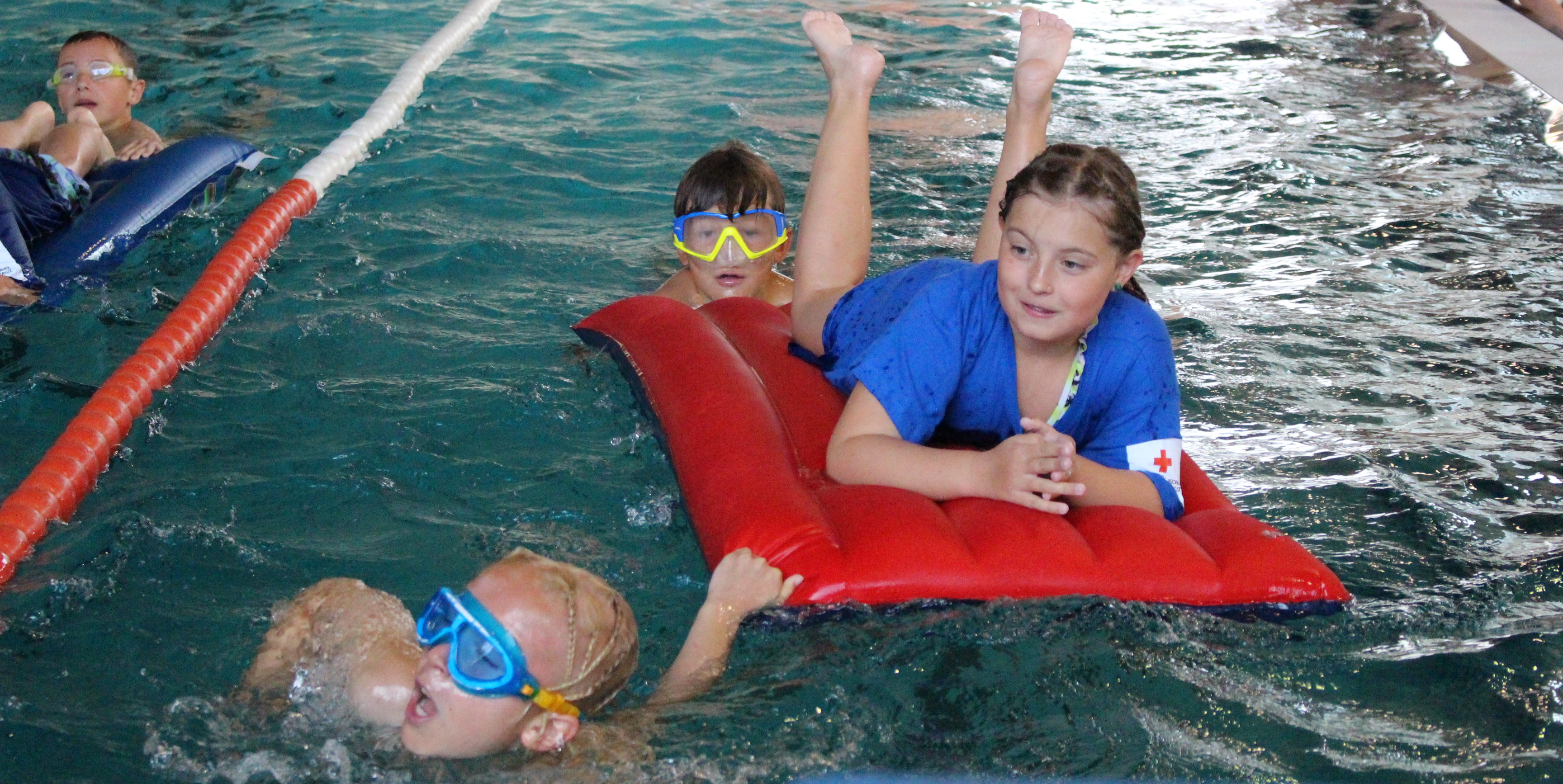 Zwei Kinder ziehen bzw. schieben ein Kind auf einer Luftmatratze im Rahmen der Rettungsstaffel beim Pinguin Cup 2023