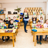Acht Kinder und eine Lehrperson halten ein Buch in die Luft.