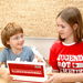 Zwei Kinder mit Verbandskassette und Jugendrotkreuz-T-Shirts