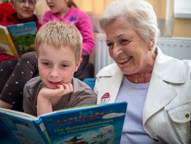 Ältere Frau mit Kind, sie lesen gemeinsam ein Buch