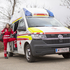 Eine junge weibliche Sanitäterin steht bei einem Rettungsauto des Roten Kreuzes