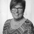 schwarz-weiß Bild einer Frau mit kurzen Haaren und Brille, die direkt in die Kamera lächelt