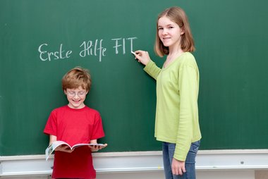 Zwei Kinder stehen vor einer Tafel