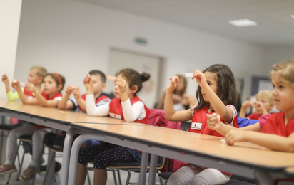 Kinder sitzen in einer Reihe und lernen Pflaster kleben