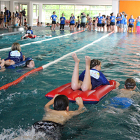 Zwei Kinder ziehen bzw. schieben ein Kind auf einer Luftmatratze im Rahmen der Rettungsstaffel beim Pinguin Cup 2023