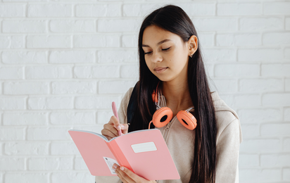 Eine Jugendliche schreibt in ein Notizbuch